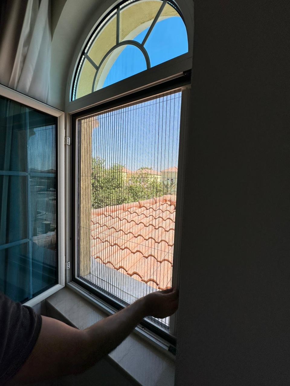 Pleated fly screen on The Lakes villa window — black frame grey mesh Dubai