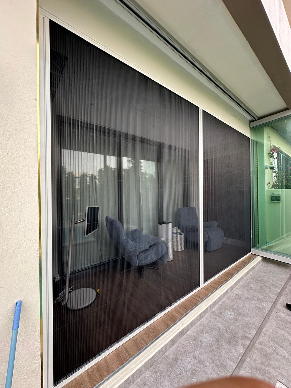 Retractable pleated fly screen on District One mega-villa garden door, white aluminium frame black mesh, Crystal Lagoon view Dubai
