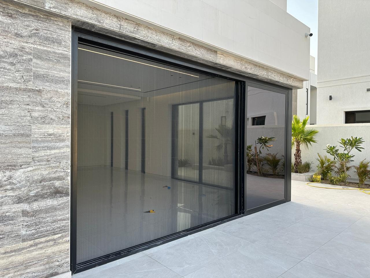 Custom fly screen installed in Dubai villa with black aluminium frame and dark grey fiber mesh