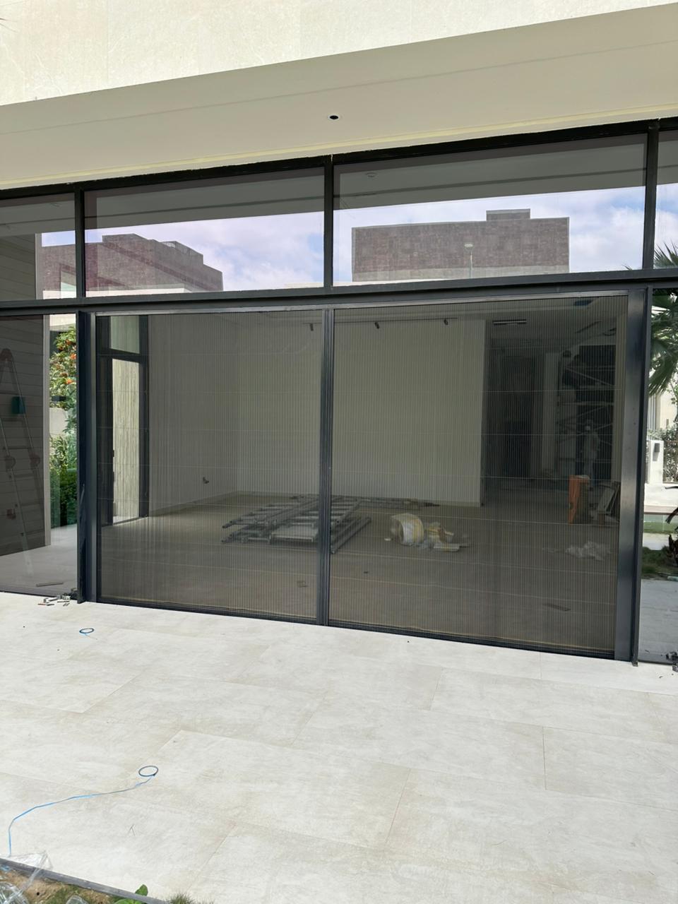 Double fly screen installation for main door in Dubai South villa with wood frame and pleated mesh
