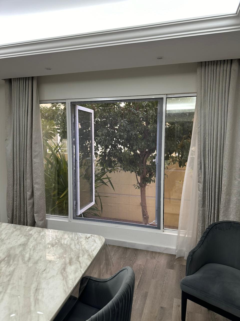 Double fly screen wide villa window Dubai white frame dark grey mosquito mesh outdoor garden flowers