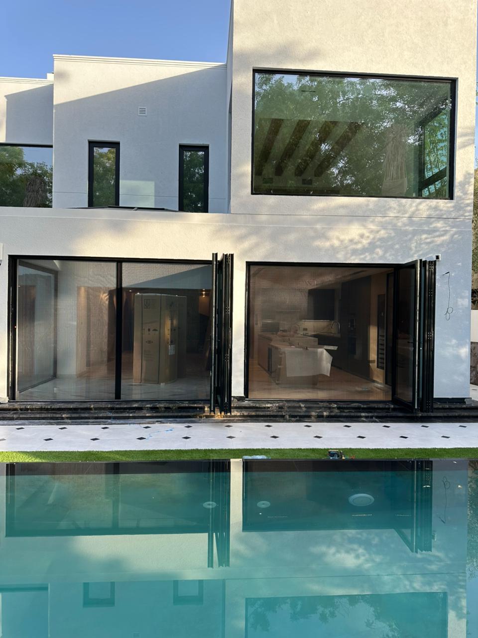 Wide double retractable fly screen on Arabian Ranches villa pool-facing patio door — white frame black mesh Dubai