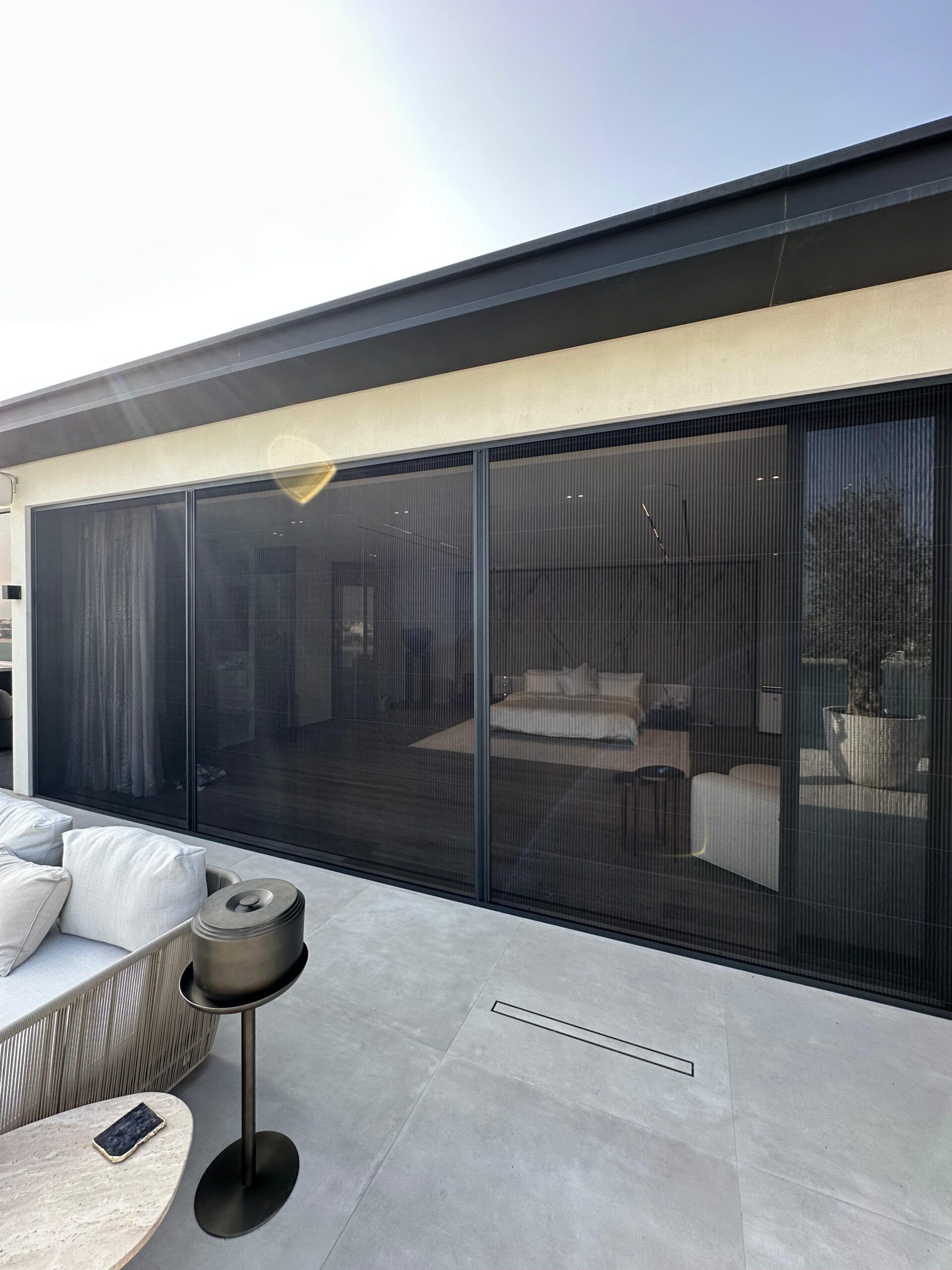 Single fly screen for window in Emirates Hills mansion with white aluminum frame and dark grey pleated mesh preserving golf course views