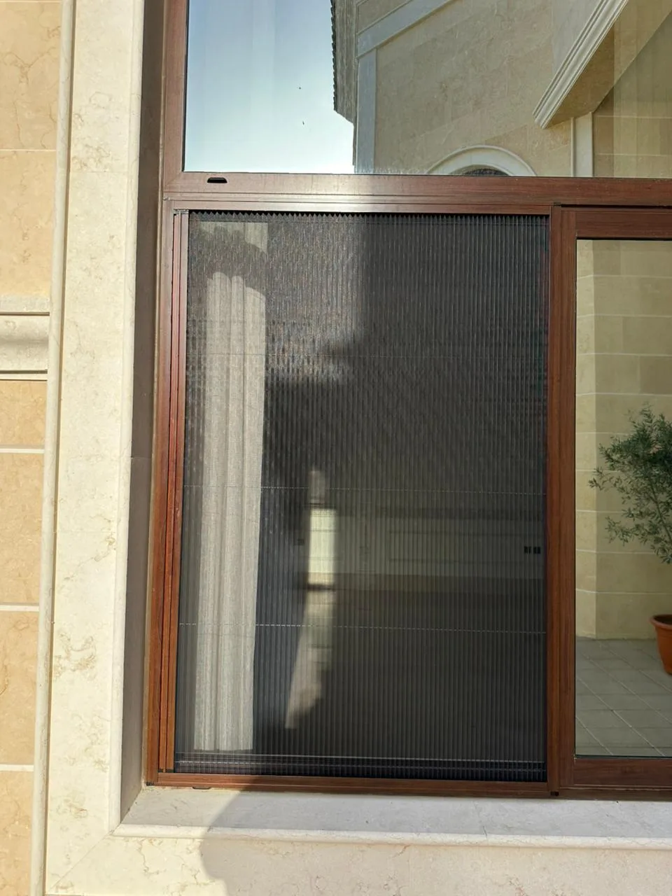 Window fly screen installed in a Dubai home with slim aluminium frame