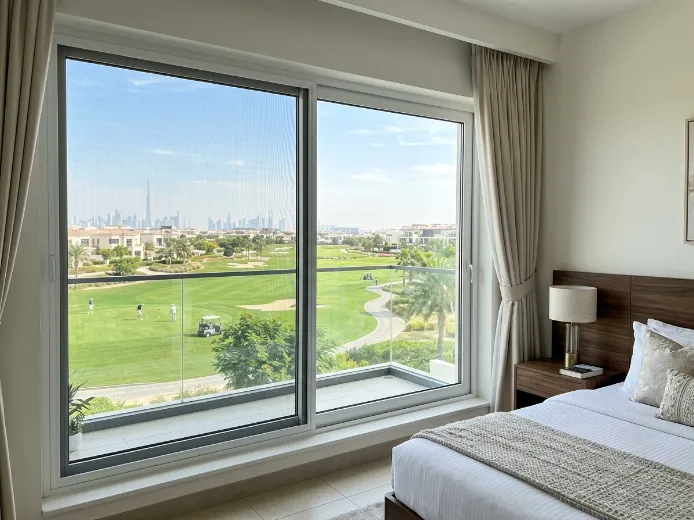 Custom fly screen on Damac Hills bedroom window overlooking golf course fairway, dark grey mesh white frame, Dubai UAE