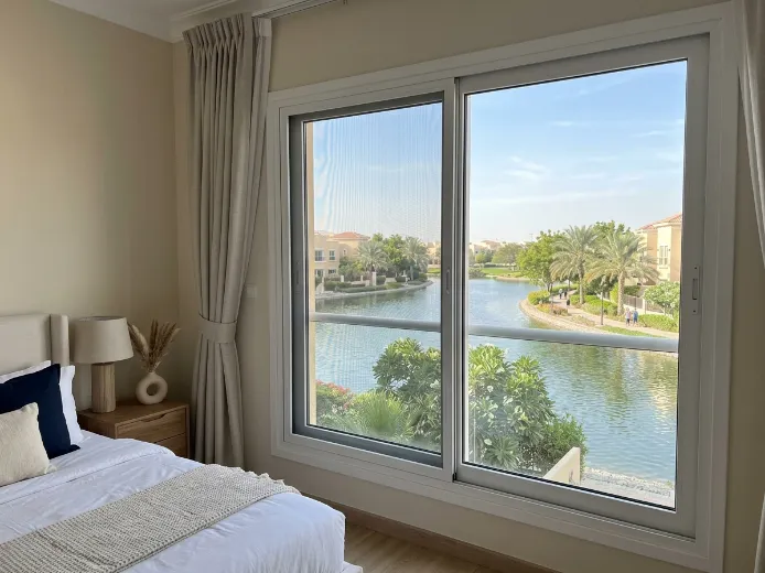 Custom fly screen on The Springs villa bedroom window overlooking community lake, dark grey mesh white frame, Dubai UAE