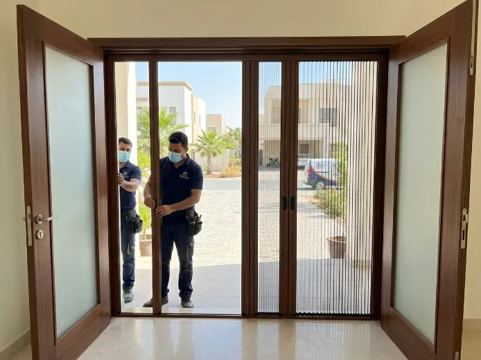 Double fly screen installation for main door in Dubai South villa with wood frame and pleated mesh